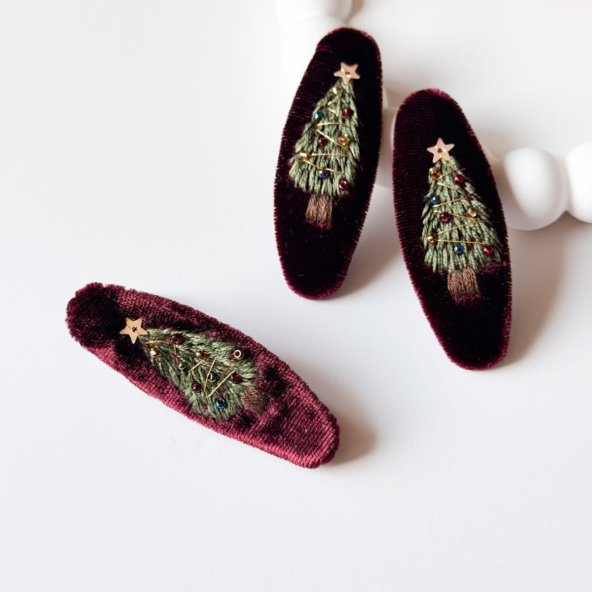 Tre mollette per capelli in velluto bordeaux con alberello di Natale ricamato verde, perline colorate e stellina dorata.